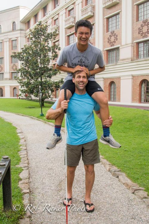 a photo of erik weihenmayer with his son arjun on his shoulders as a teenager