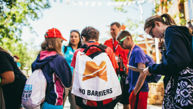 a photo of a group of kids with a no barriers flag huddling up for a scavenger hunt