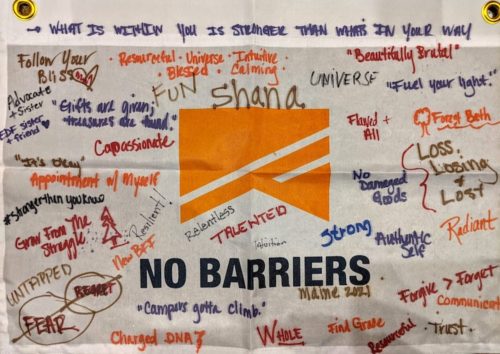 Blog post feature image: A No Barriers Flag with words of empowerment handwritten on it in sharpie, part of an exercise focused on resiliency, hope, and healing that took place at the 2021 No Barriers Caregivers Retreats at the Adaptive Outdoor Education Center in Carrabassett Valley, Maine.
