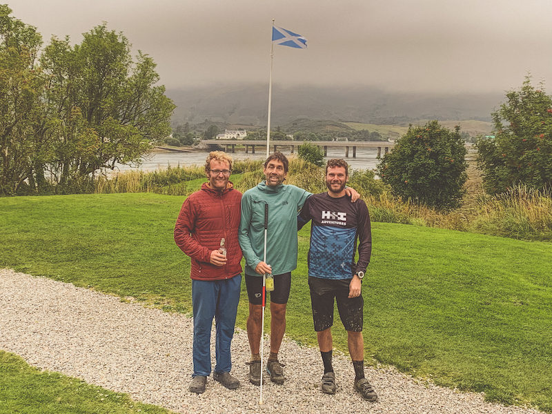 Erik, Daniel and guide gather for a group shot with the Scottish flag waving behind them. Credit: Daniel Bedell. 