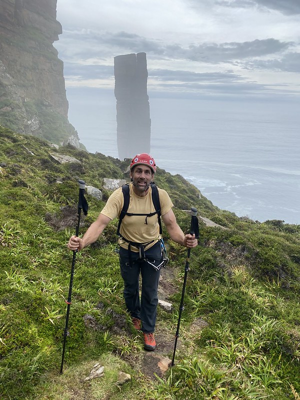 Erik hiking in climbing gear with Old Man of Hoy rising up in the background. Credit: Timmy O'Neill. 