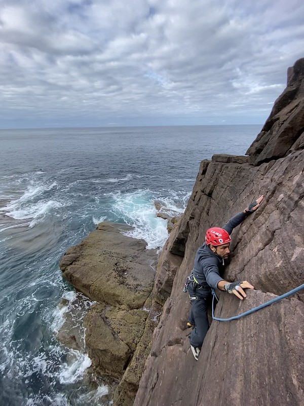 Erik climbing on the sea stacks, arms spread wide searching for purchase. Credit: Timmy O'Neill. 