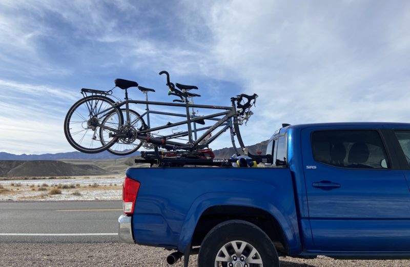 A blue truck carrying two (2) tandem bikes in Death Valley.