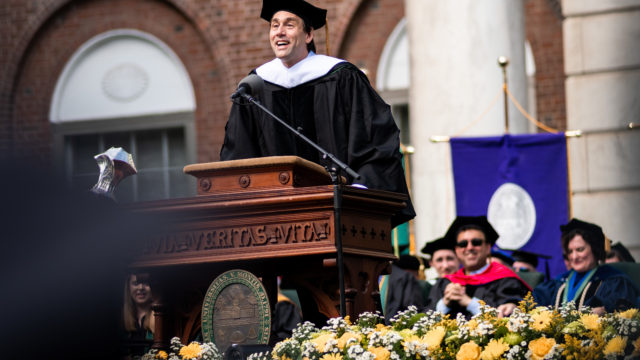 Erik leaning forward at the lectern as he gives his commencement address