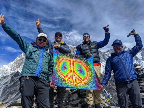Erik, Timmy O'Neill and two Sherpas hold a tie-dye peace flag at a stop point climbing Ama Dablam in Nepal's Himalayan Range.