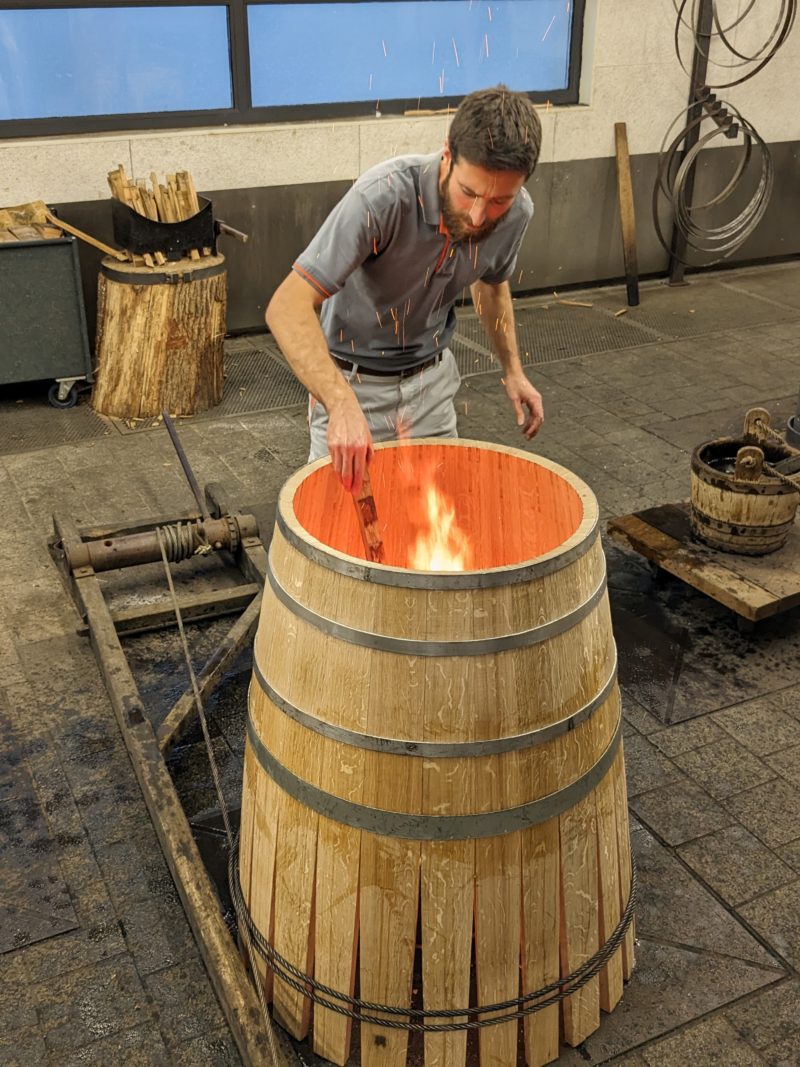 A cooper "toasting" the barrel they are making. 